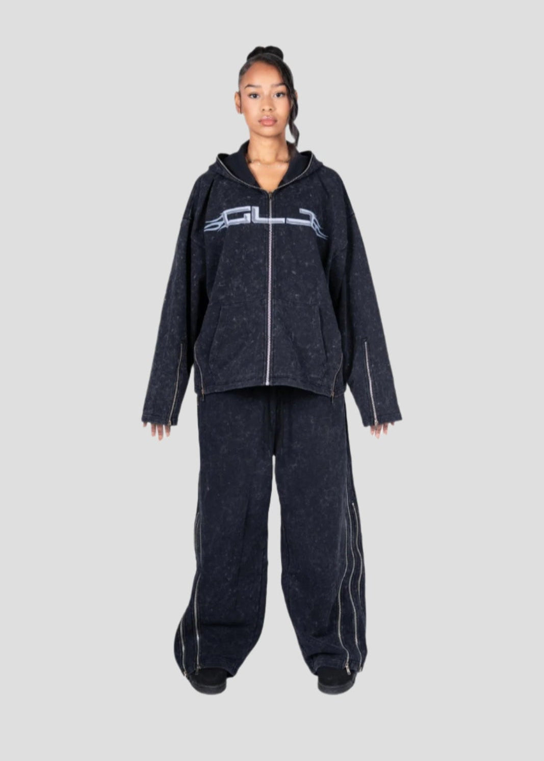 Person wearing a dark hoodie and pants set with a GLJ (Girls like jet ski)logo on a light gray background