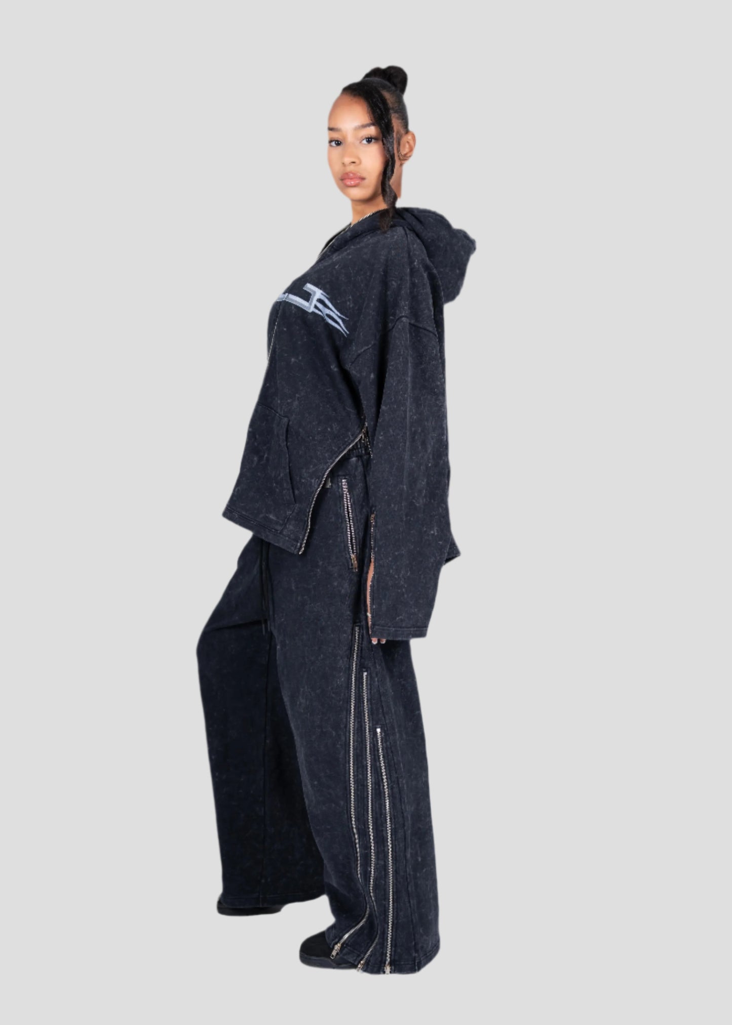 Person wearing a dark hoodie and pants set with a GLJ (Girls like jet ski)logo on a light gray background