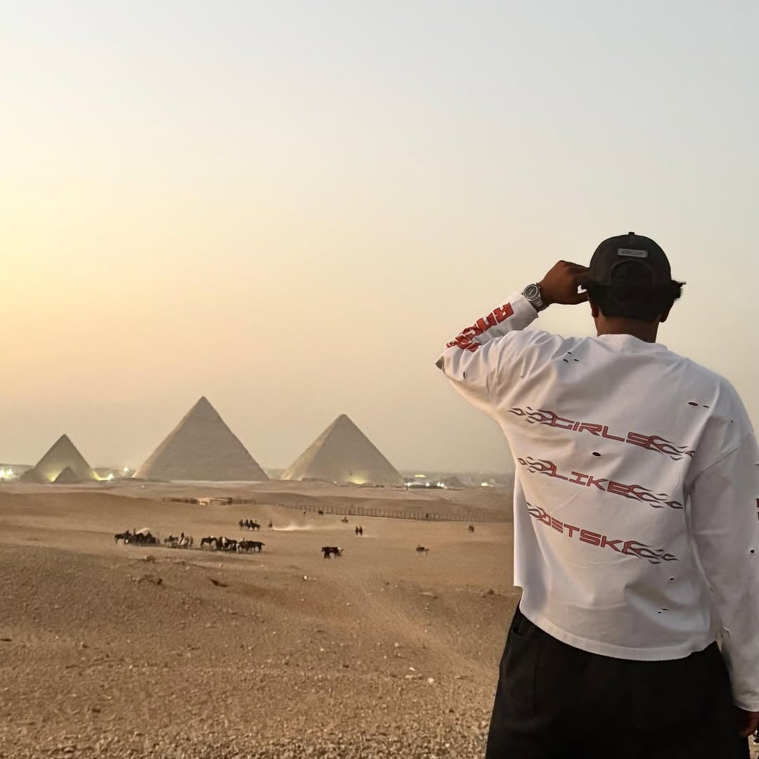 Person standing in front of the Pyramids of Giza at sunset.